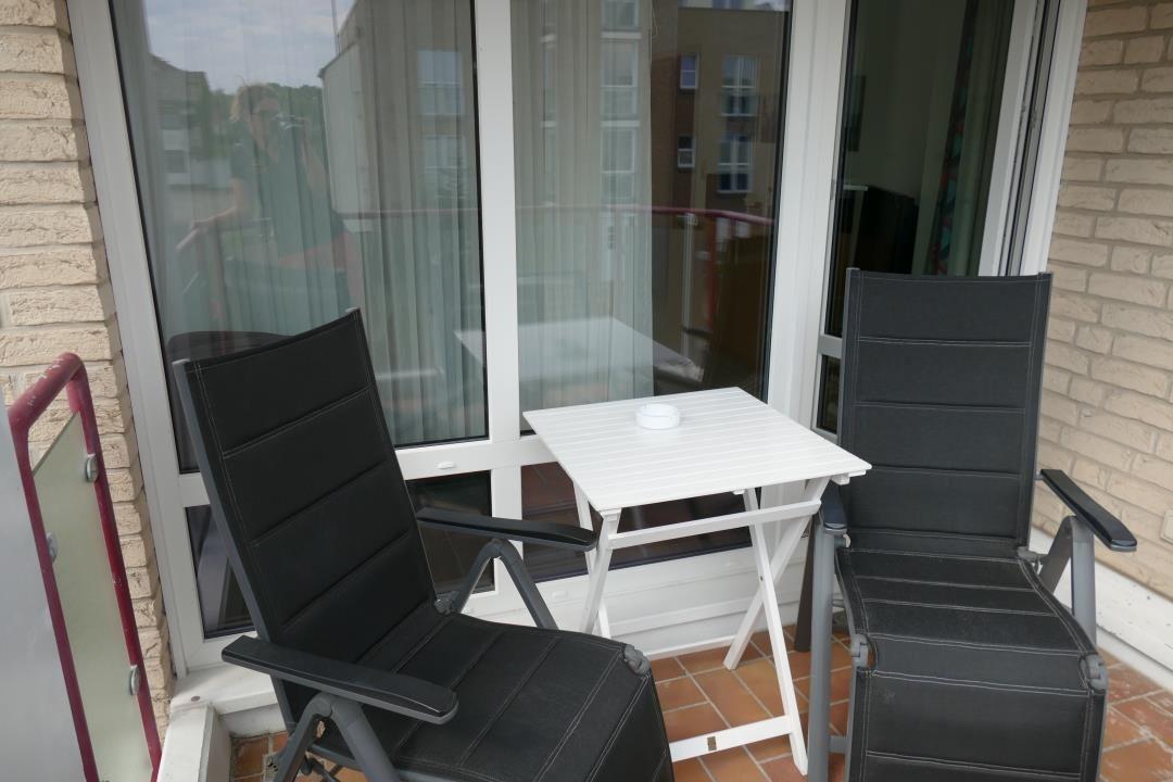 Terrace with two black chairs and a white table.