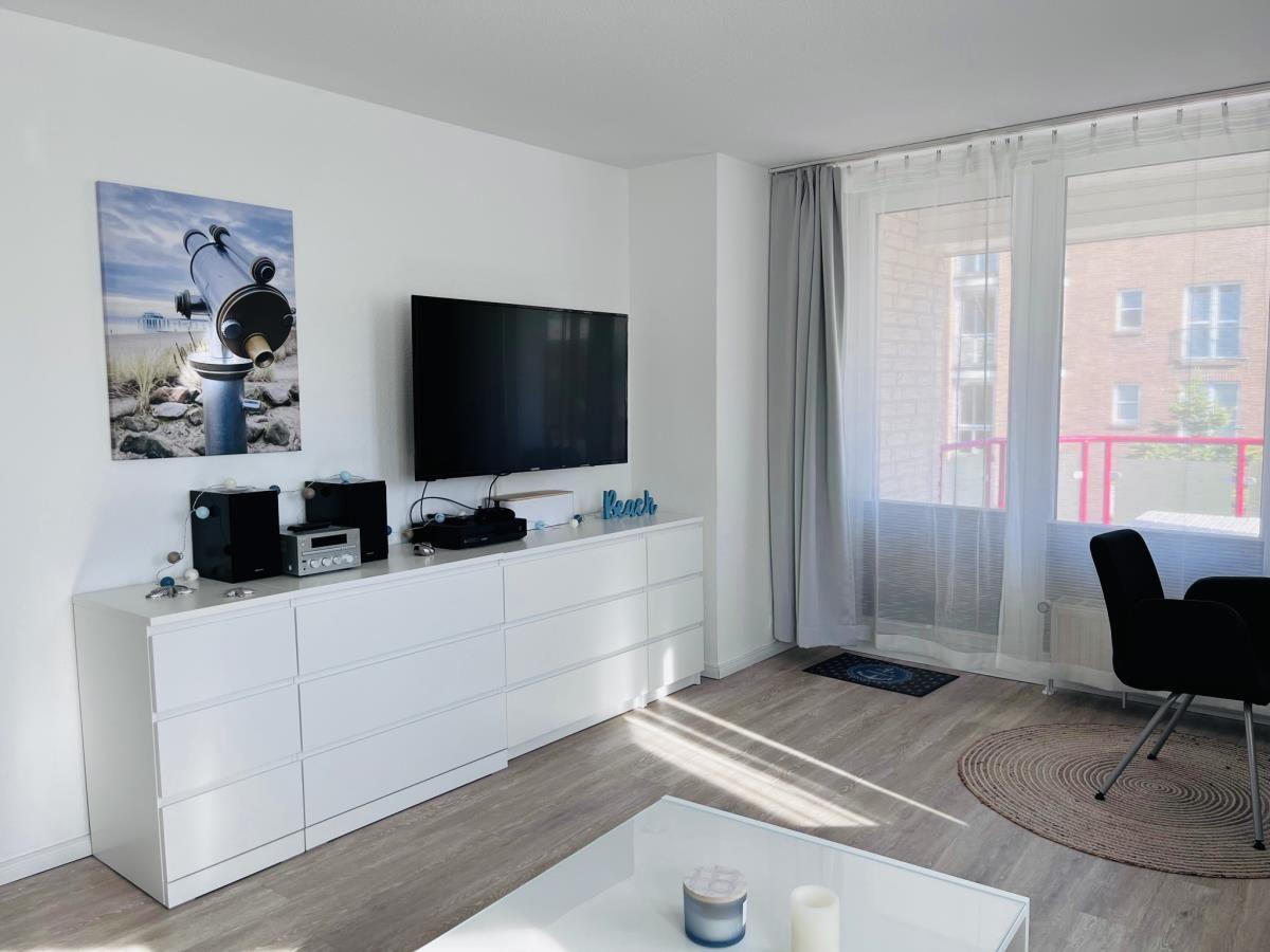 Living room with TV, cabinet, and balcony view