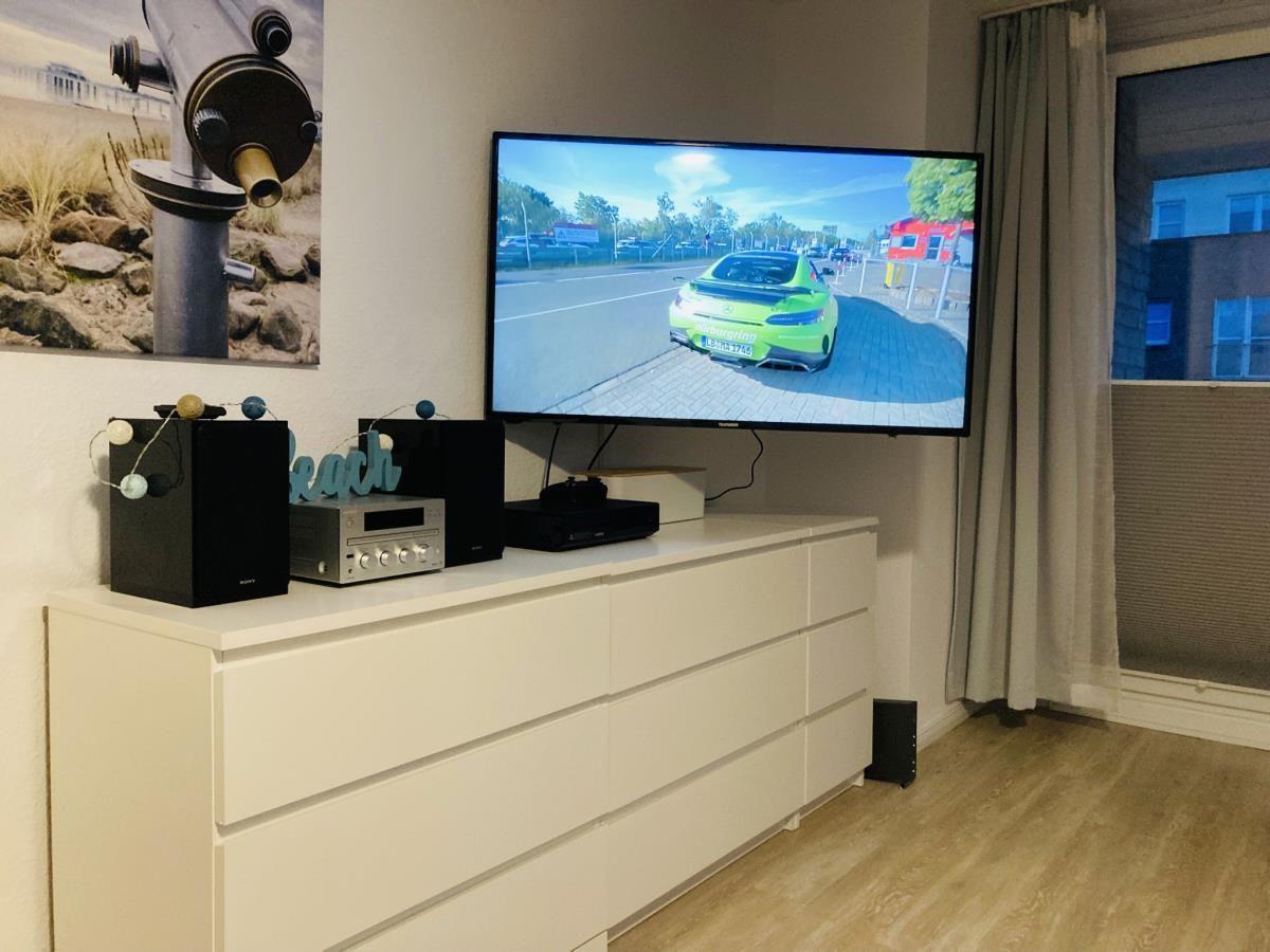 TV on white dresser with speakers and game consoles