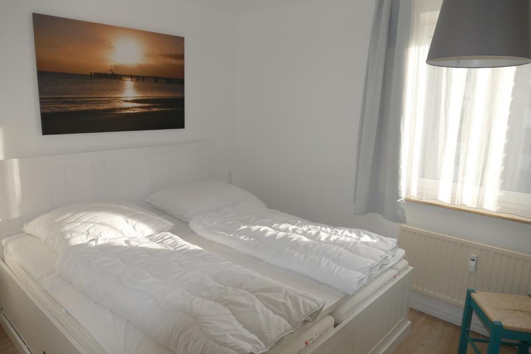 Bedroom with double bed, wall picture, and window with curtains.