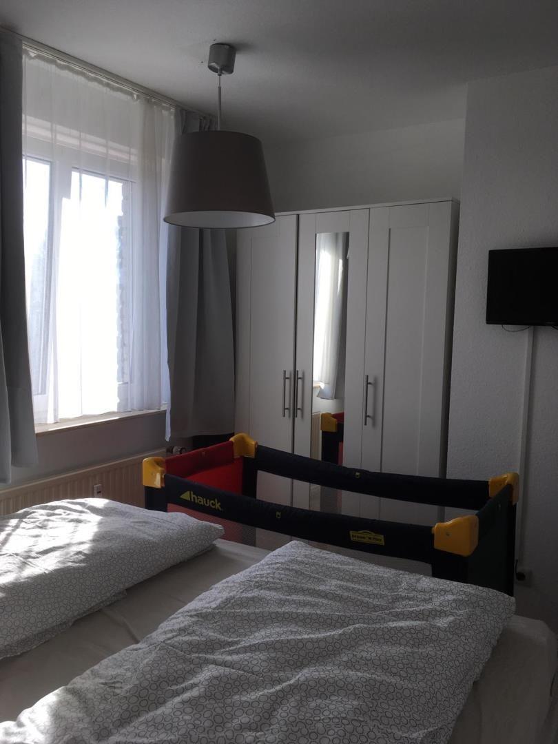 Bedroom with bed, child bed, wardrobe, and window.