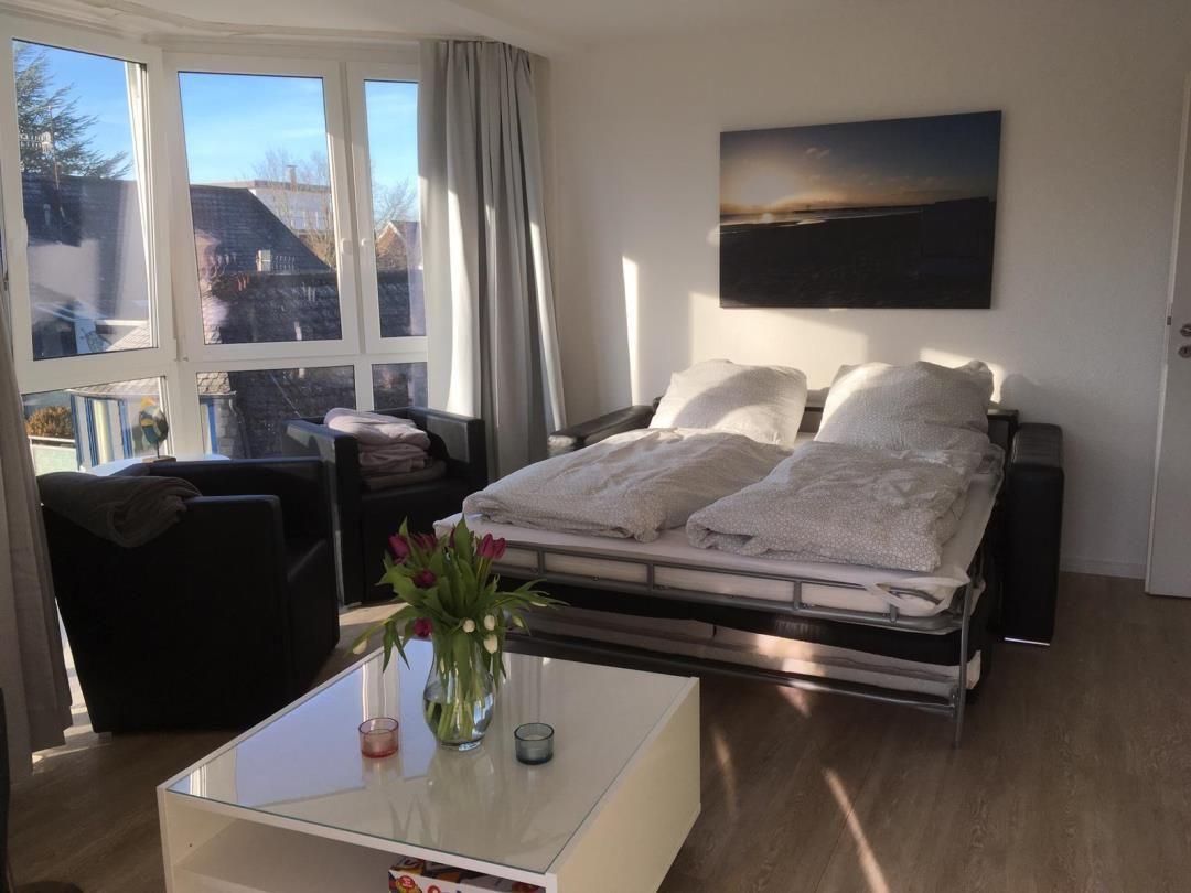 Bedroom with bed, seating, and windows for views.