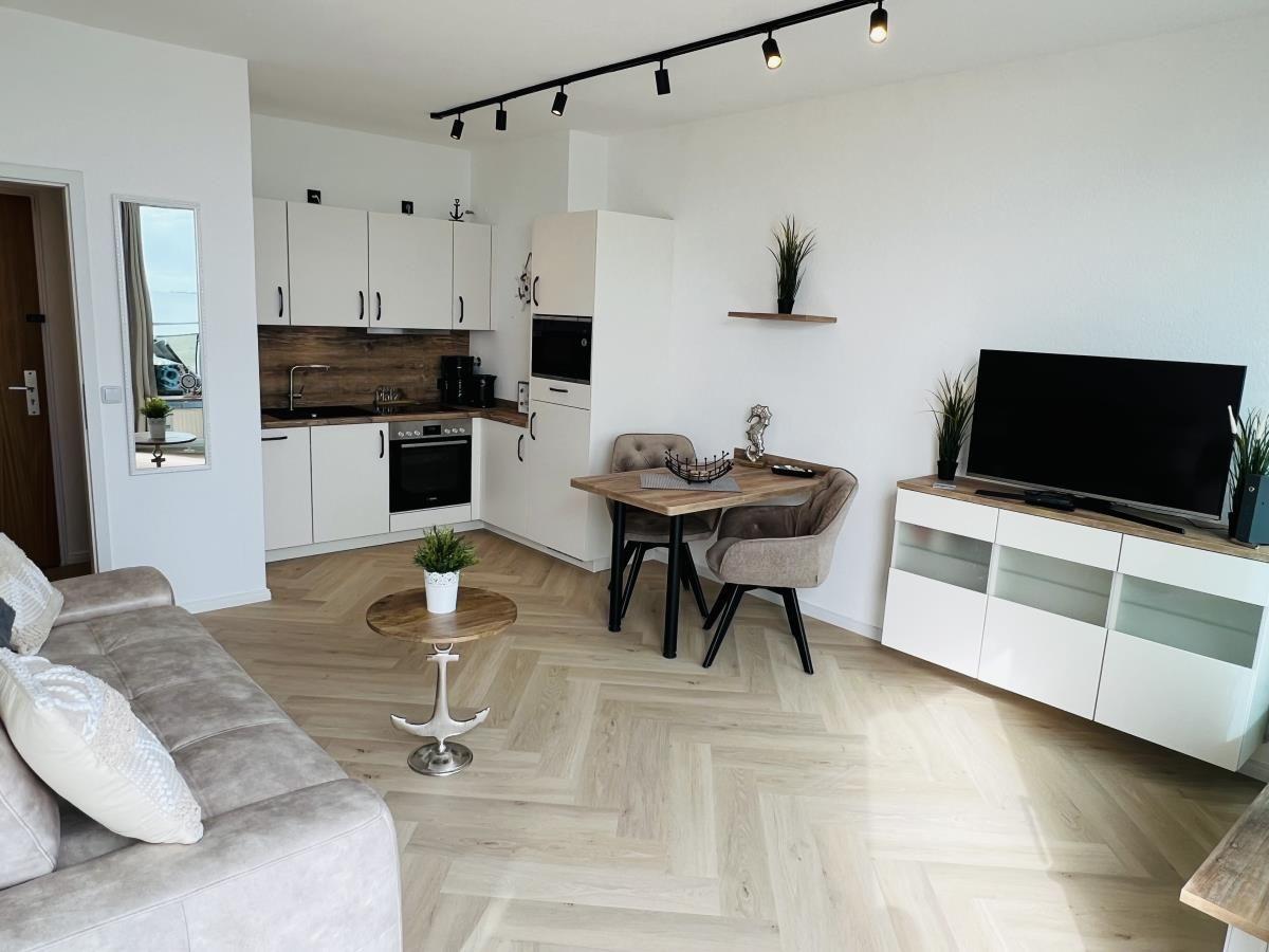 Wohnung mit Küche, Essbereich und Wohnzimmer mit Holzboden und moderner Einrichtung.