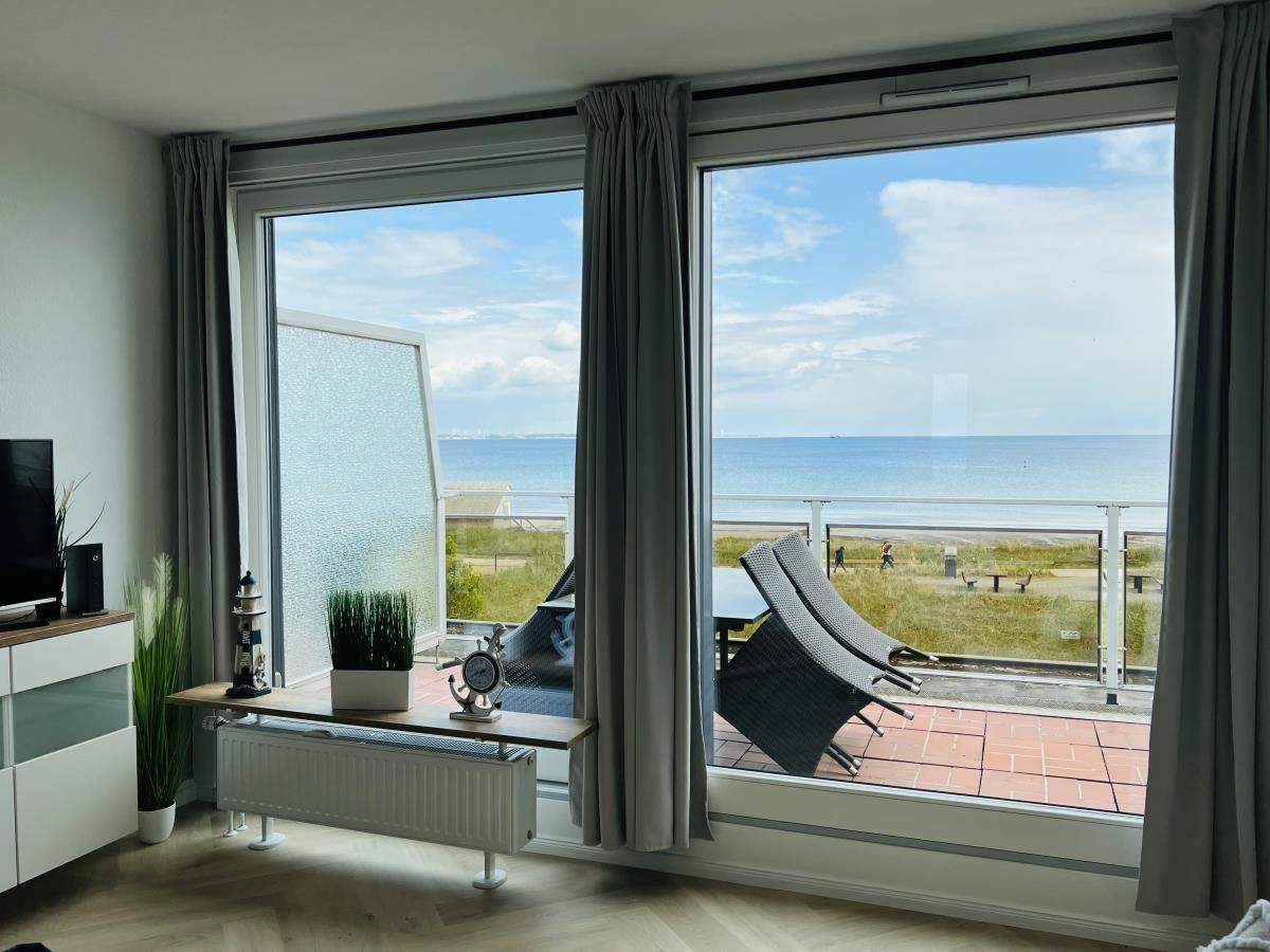 Wohnzimmer mit Meerblick, Balkon und Sitzgelegenheiten.