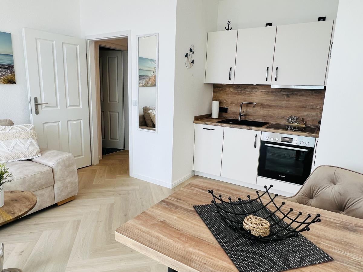 Wohn- und Küchenbereich mit Holzboden und moderner Einbauküche.