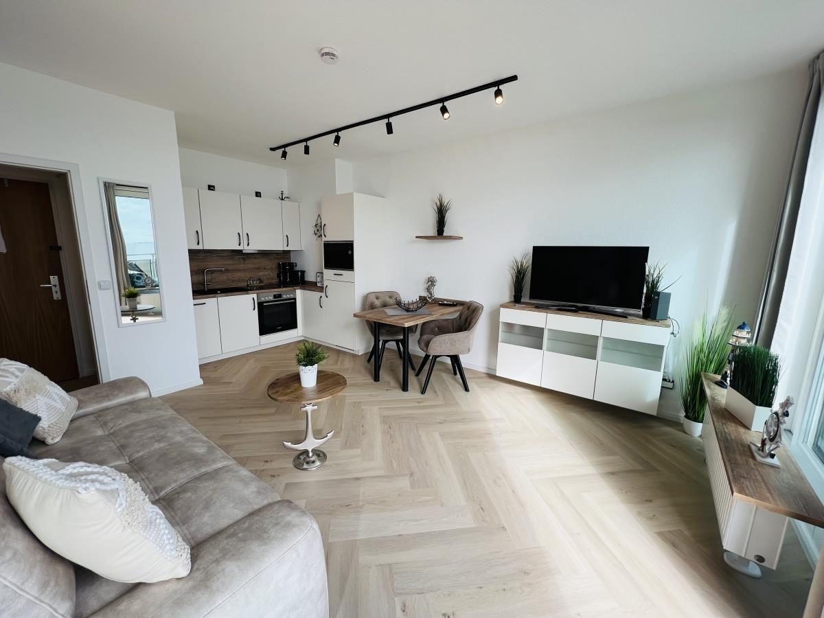 Wohnung mit Küche, Essbereich und TV. Holzboden und moderne Einrichtung.