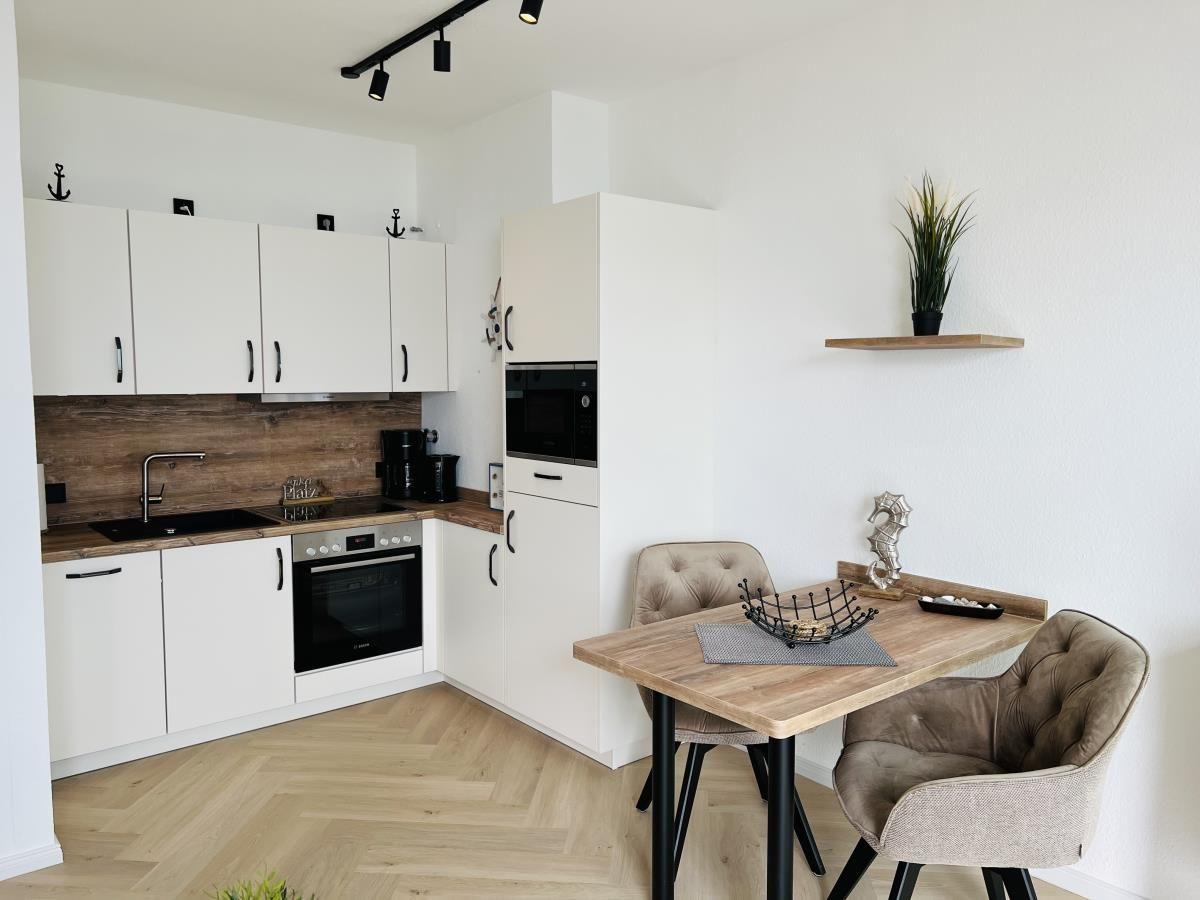 Küche mit Essbereich, weißen Schränken und Holzboden