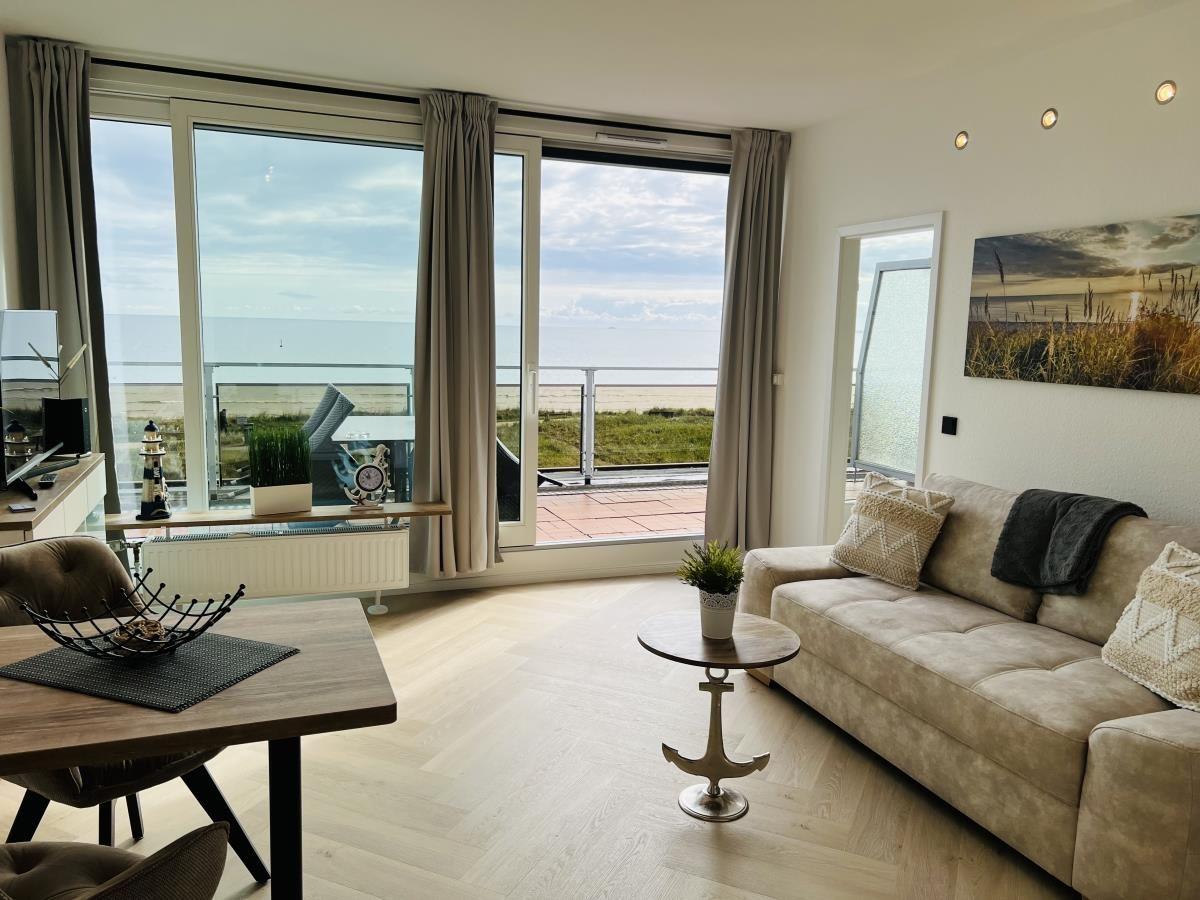 Wohnzimmer mit Meerblick, Sofa, Tisch und Balkon.