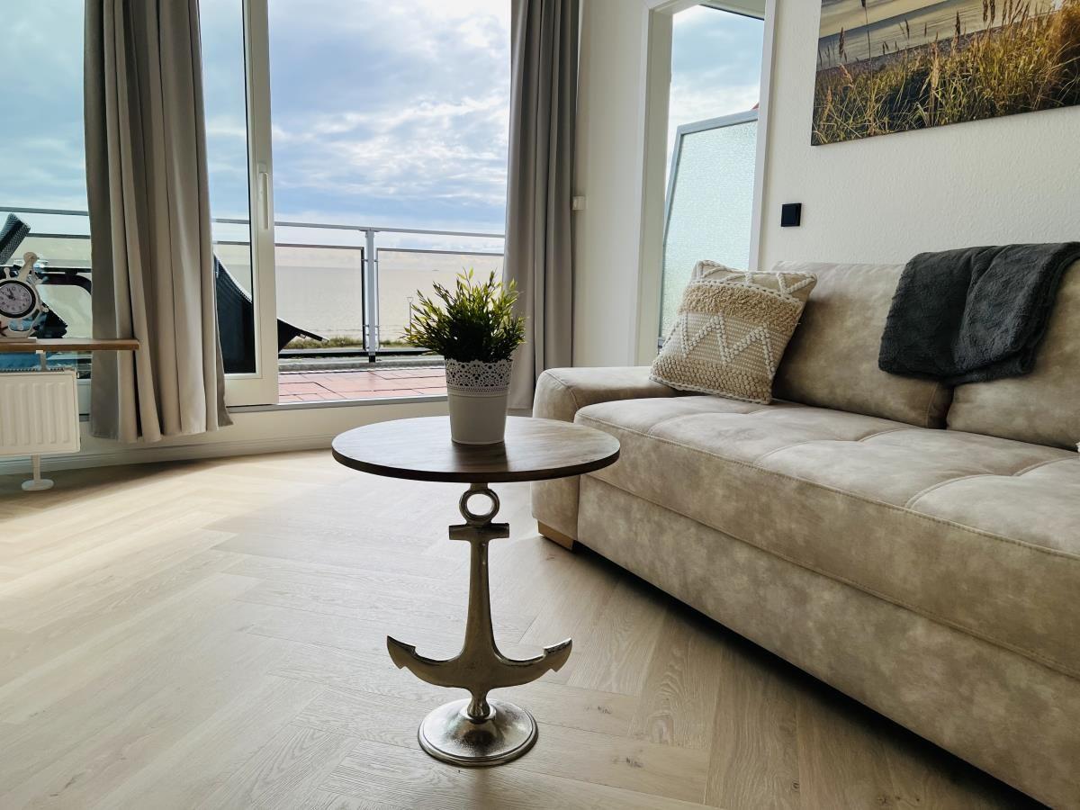 Wohnzimmer mit Sofa, Tisch und Blick auf Balkon.