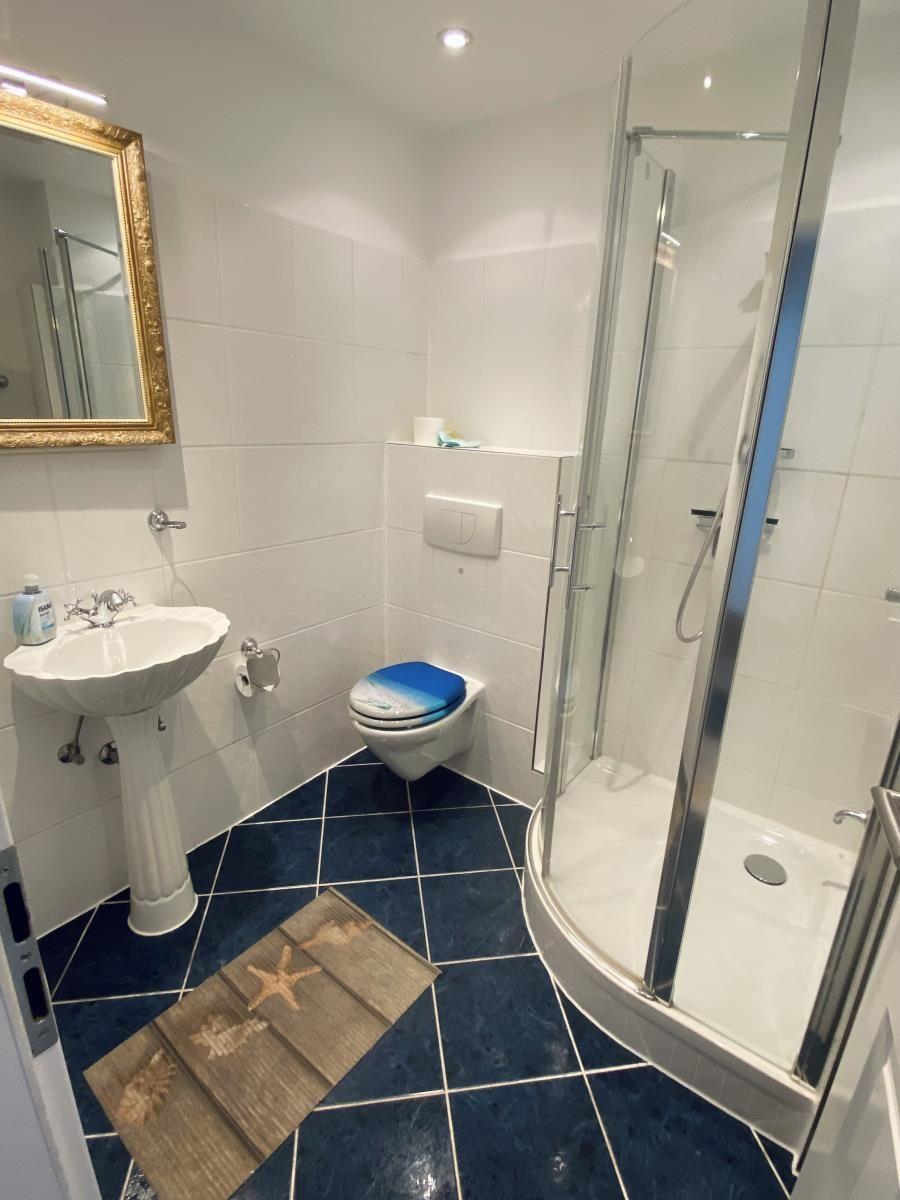 Badezimmer mit Dusche, Toilette und Waschbecken mit Spiegel.