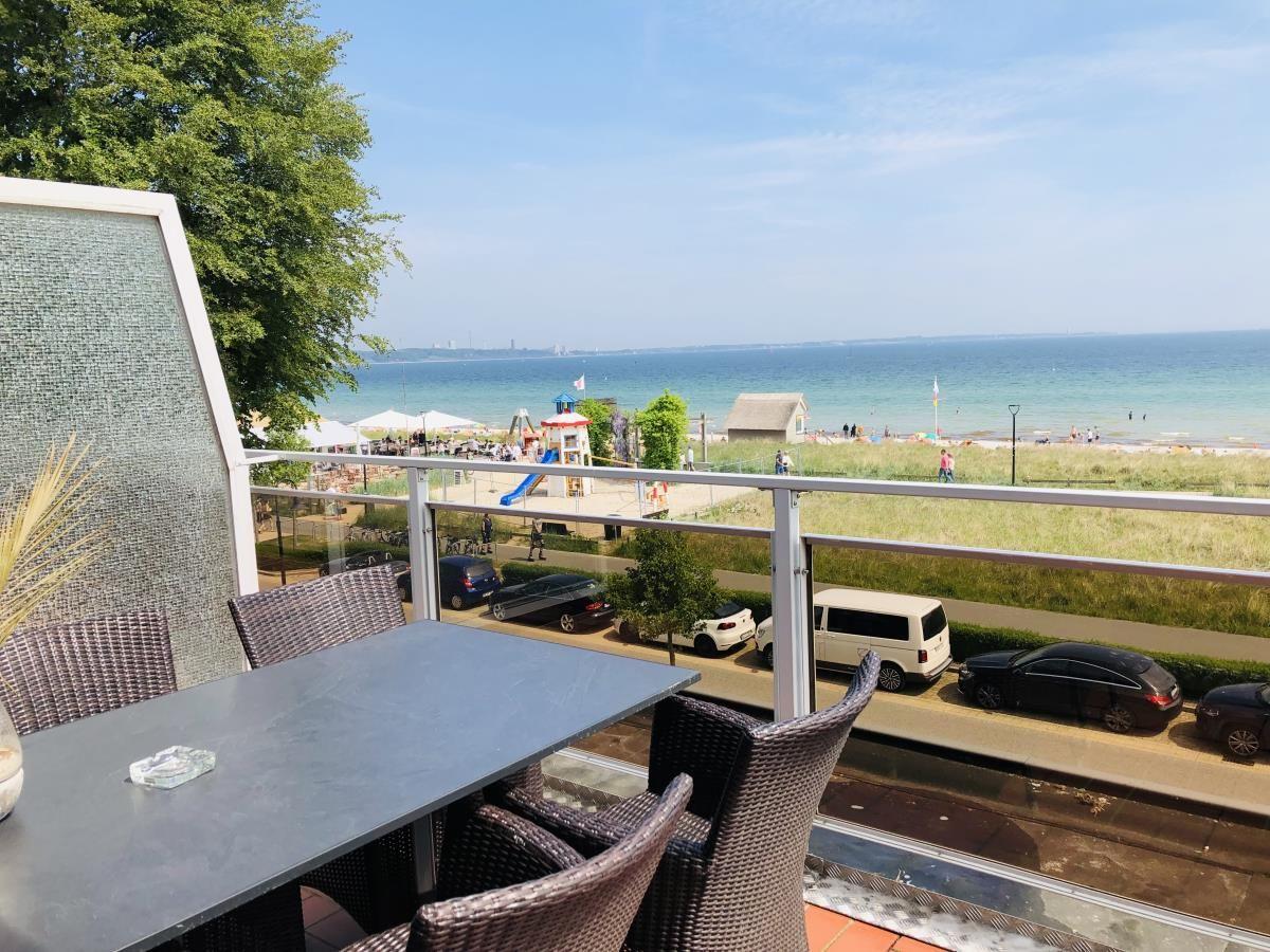 Terrasse mit Tisch und Stühlen bietet Blick auf Strand und See.