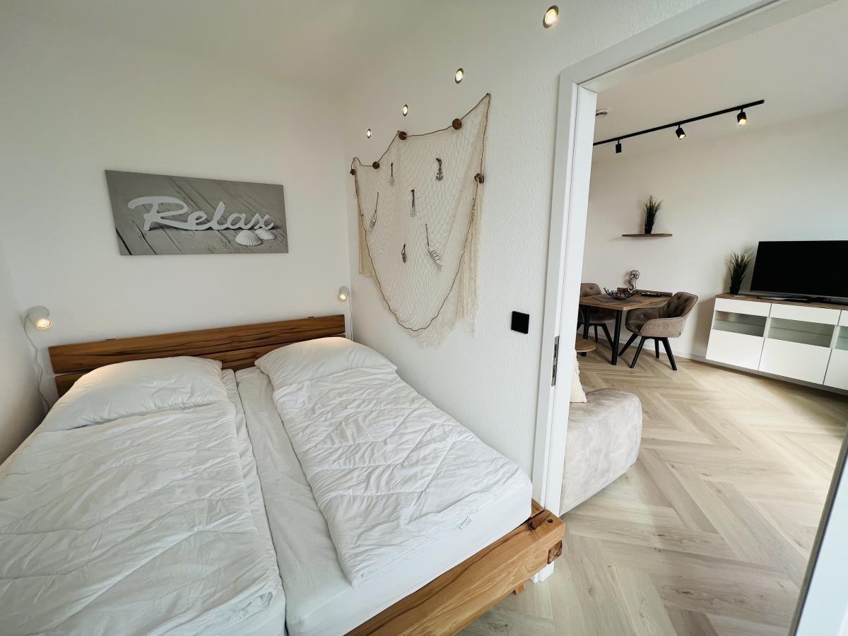 Schlafzimmer mit Doppelbett und Blick in Wohnbereich mit Esstisch.