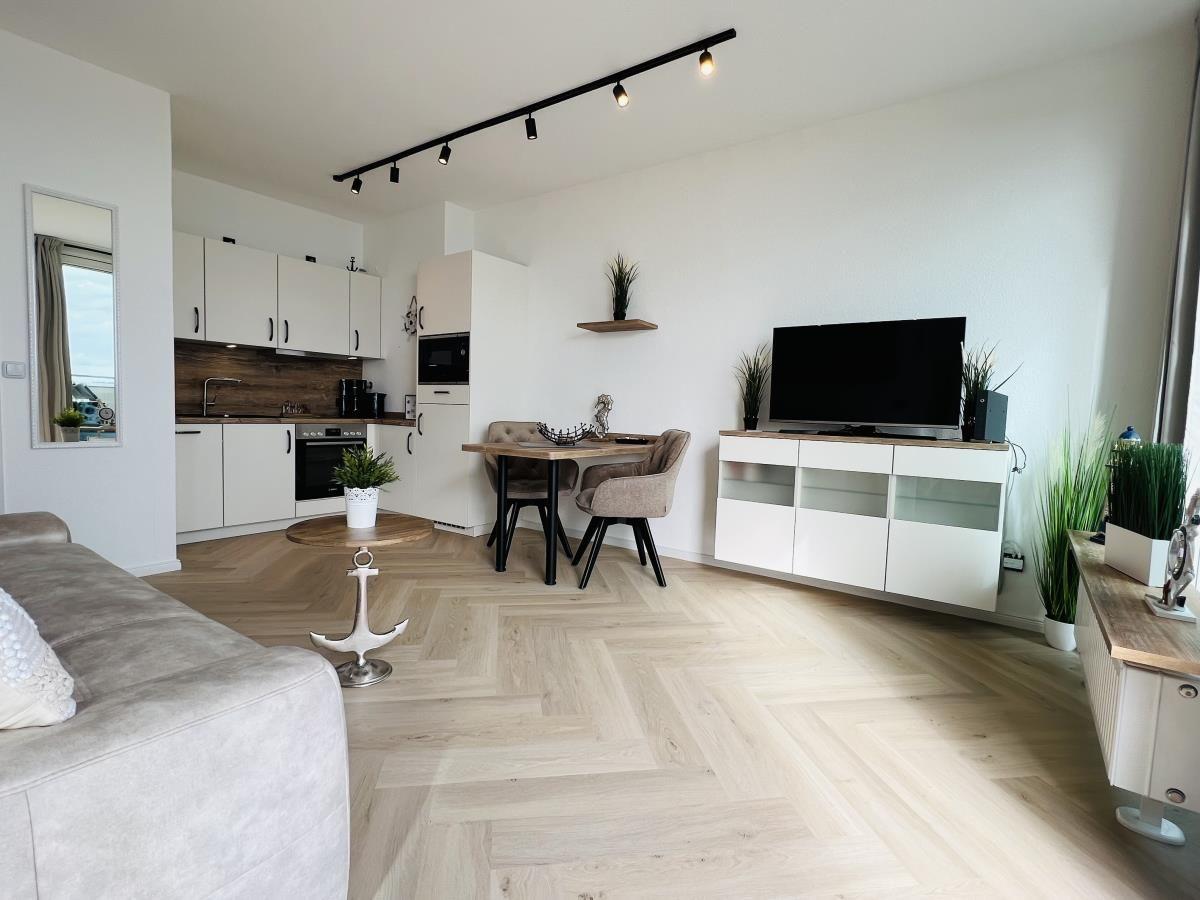 Wohnung mit Küche, Essbereich und TV. Holzboden und moderne Einrichtung.