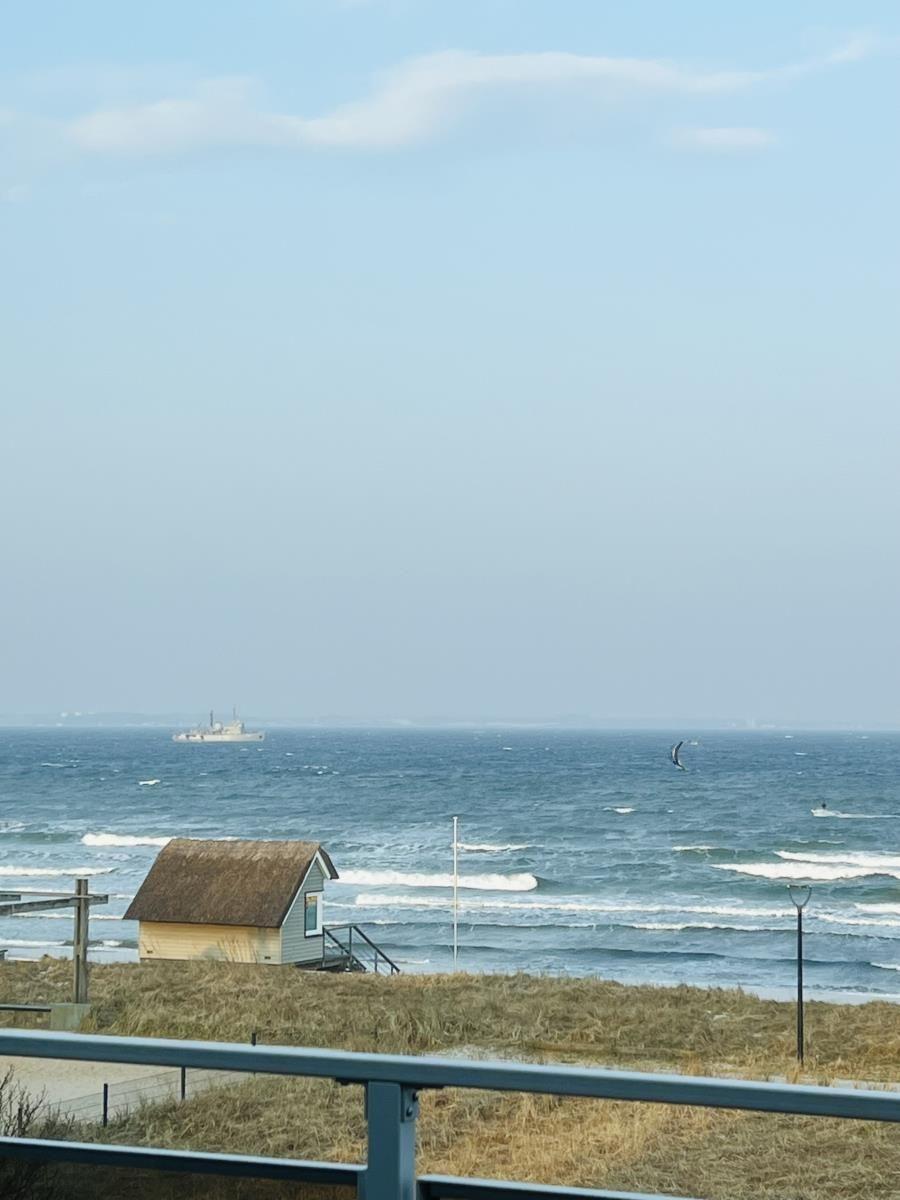 Meer mit Surfer und kleinem Haus im Vordergrund.