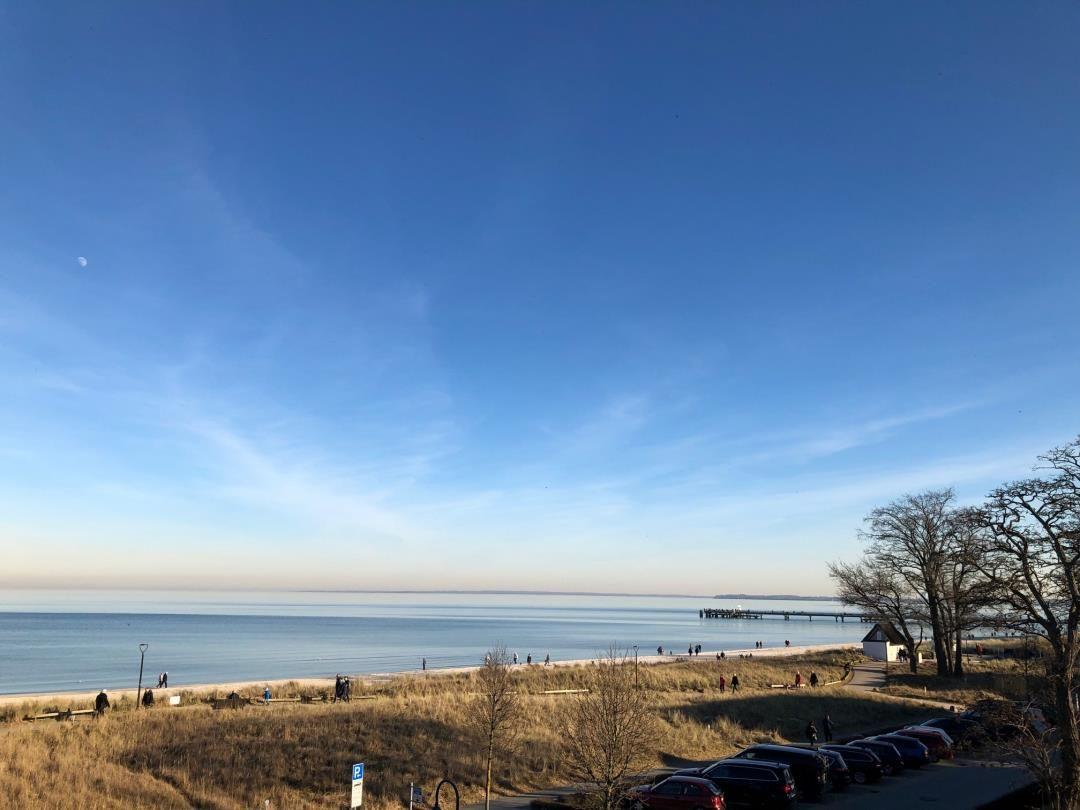 Strand mit Steg und Parkplatz unter klarem Himmel
