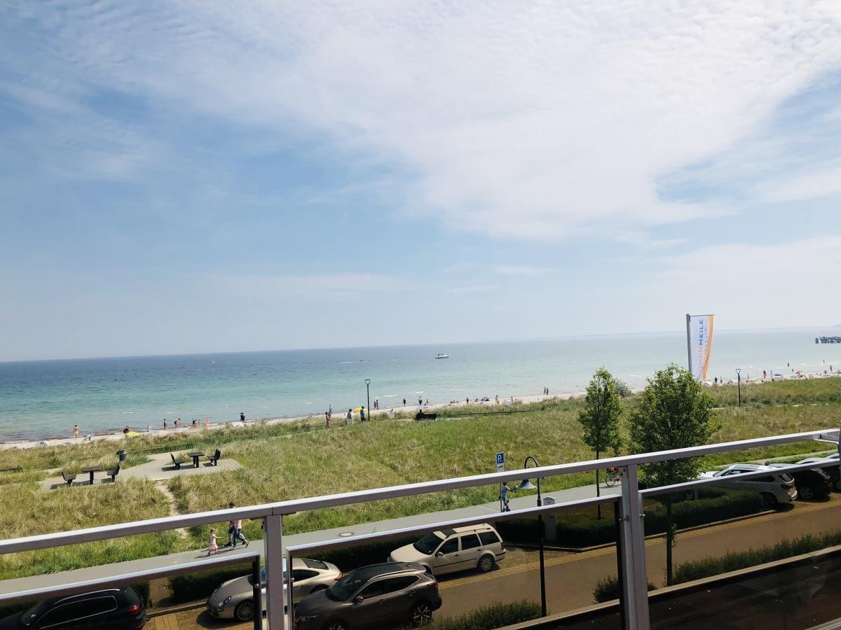 Blick auf Strand, Meer und Parkbereich mit Parkplätzen und Bäumen.