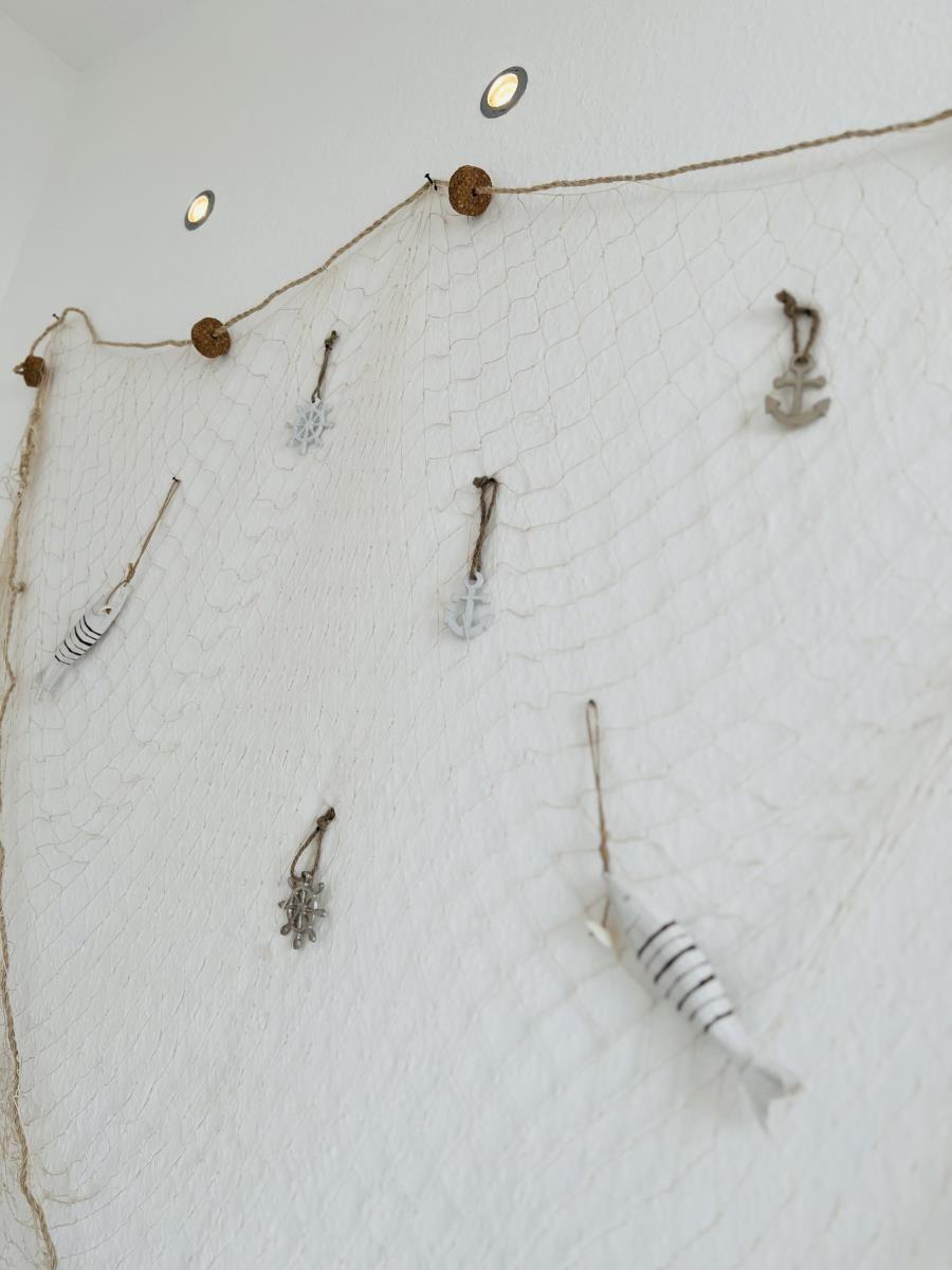 Wand mit Fischerdekoration aus Netz und Ankeranhängern.