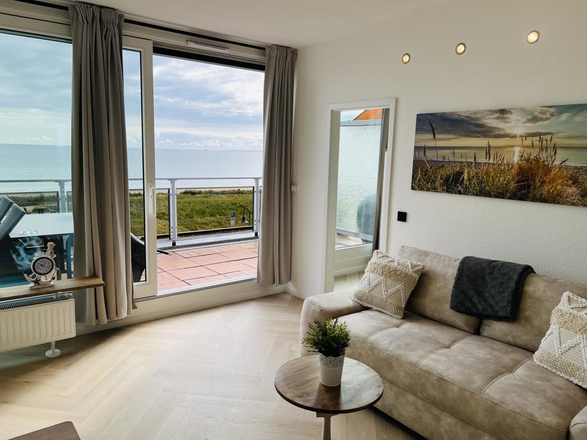 Wohnzimmer mit Sofa, Blick auf Terrasse und Meer.