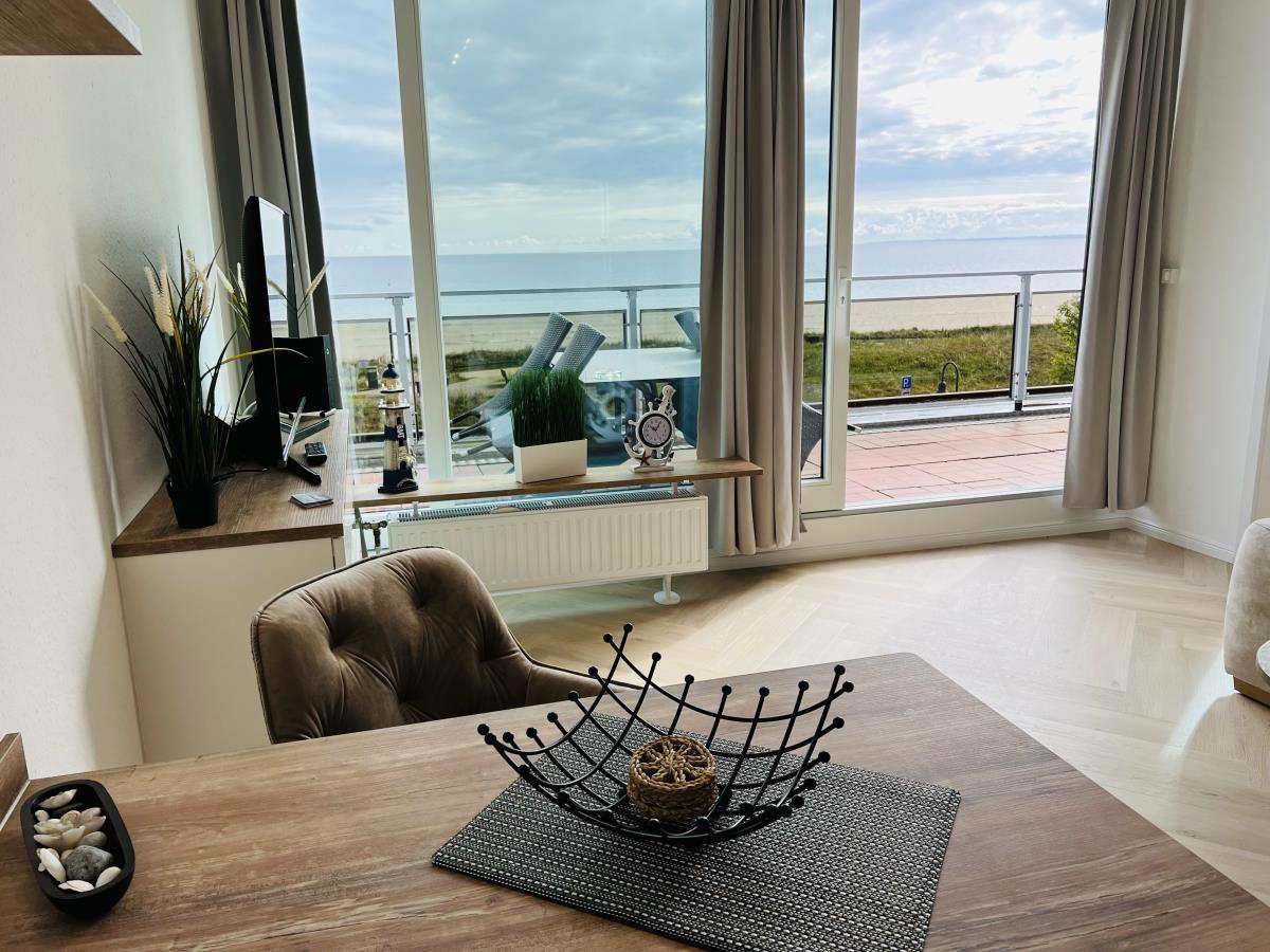 Wohnbereich mit Blick auf den Strand und das Meer durch große Fenster.