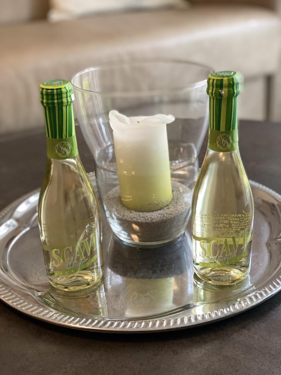Silberner Tablett mit zwei Flaschen und einer Kerze in einem Glas.