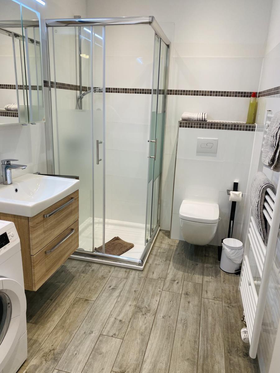Badezimmer mit Dusche, Waschbecken und Toilette auf Holzdielen