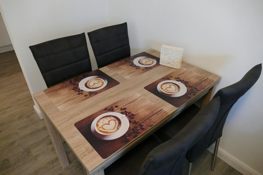 Esstisch mit vier Stühlen und Kaffeemotiv-Tischdecken.