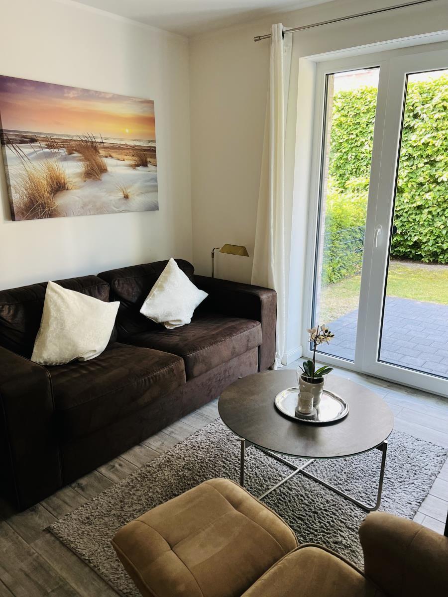 Wohnzimmer mit Sofa, Tisch und Blick auf den Garten.