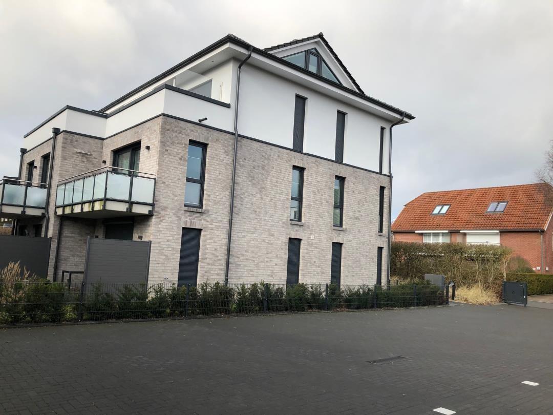 Moderne Villa mit Balkon und gepflastertem Vorplatz.