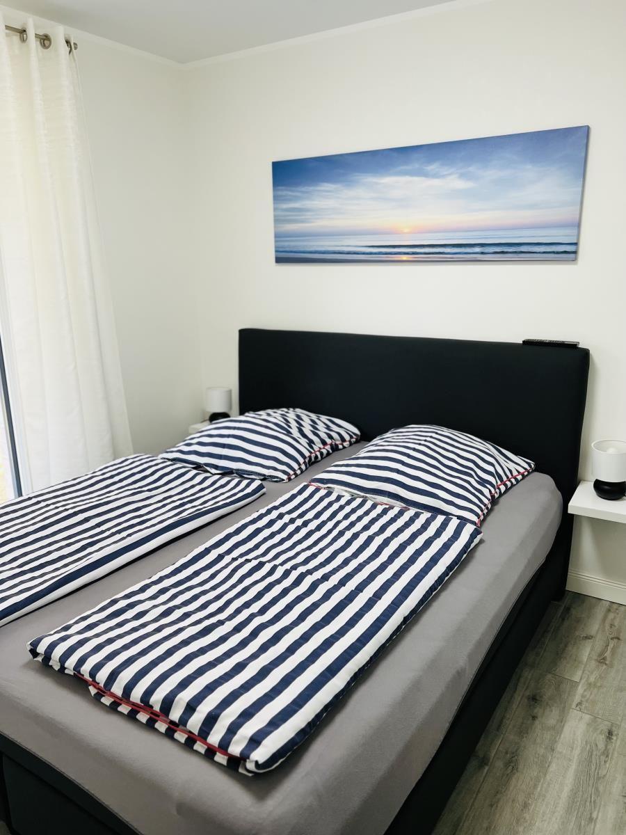 Schlafzimmer mit Doppelbett, Wandbild und Nachttischen.
