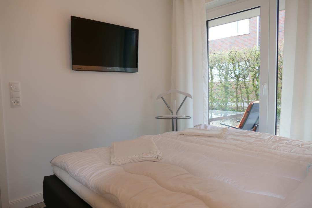 Schlafzimmer mit Bett, TV und Fenster zum Balkon.