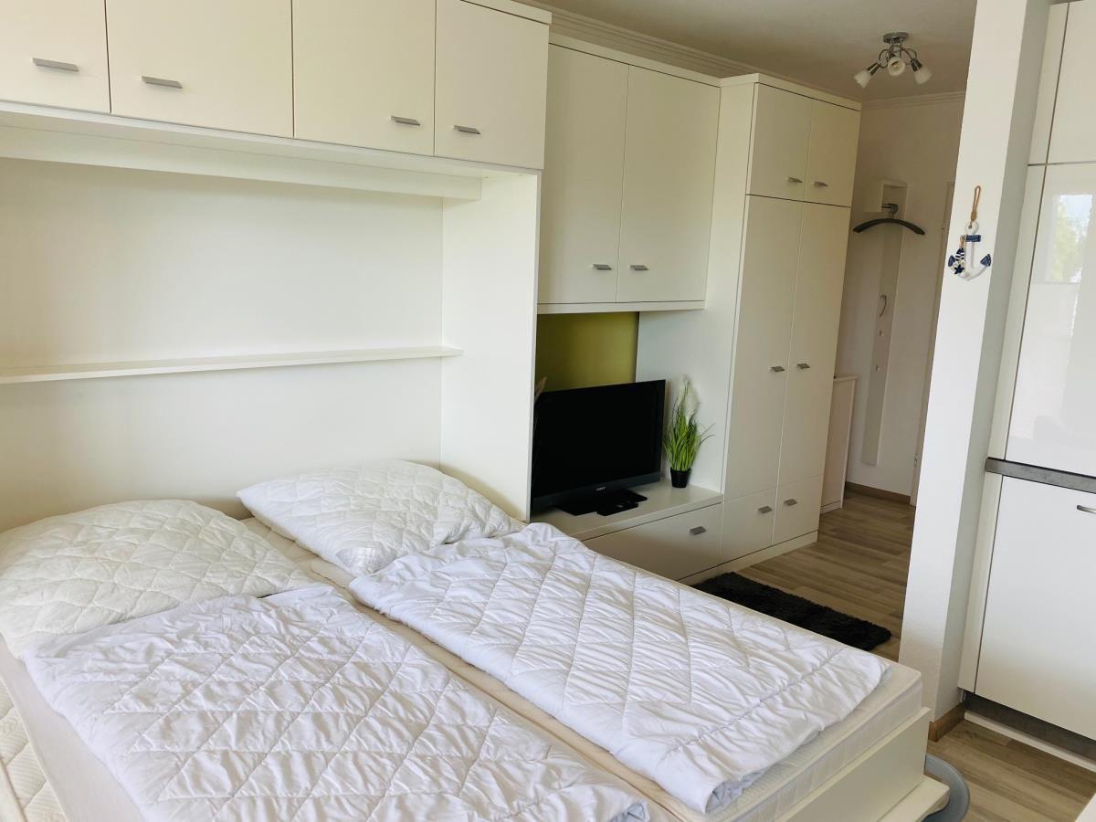 Schlafzimmer mit Bett, TV und weißen Schränken