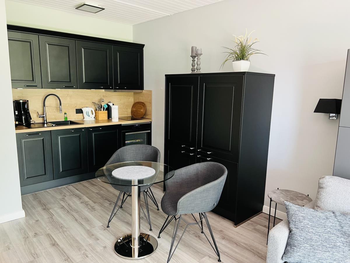 Kitchen with dining table, black cabinets, and living area with sofa.