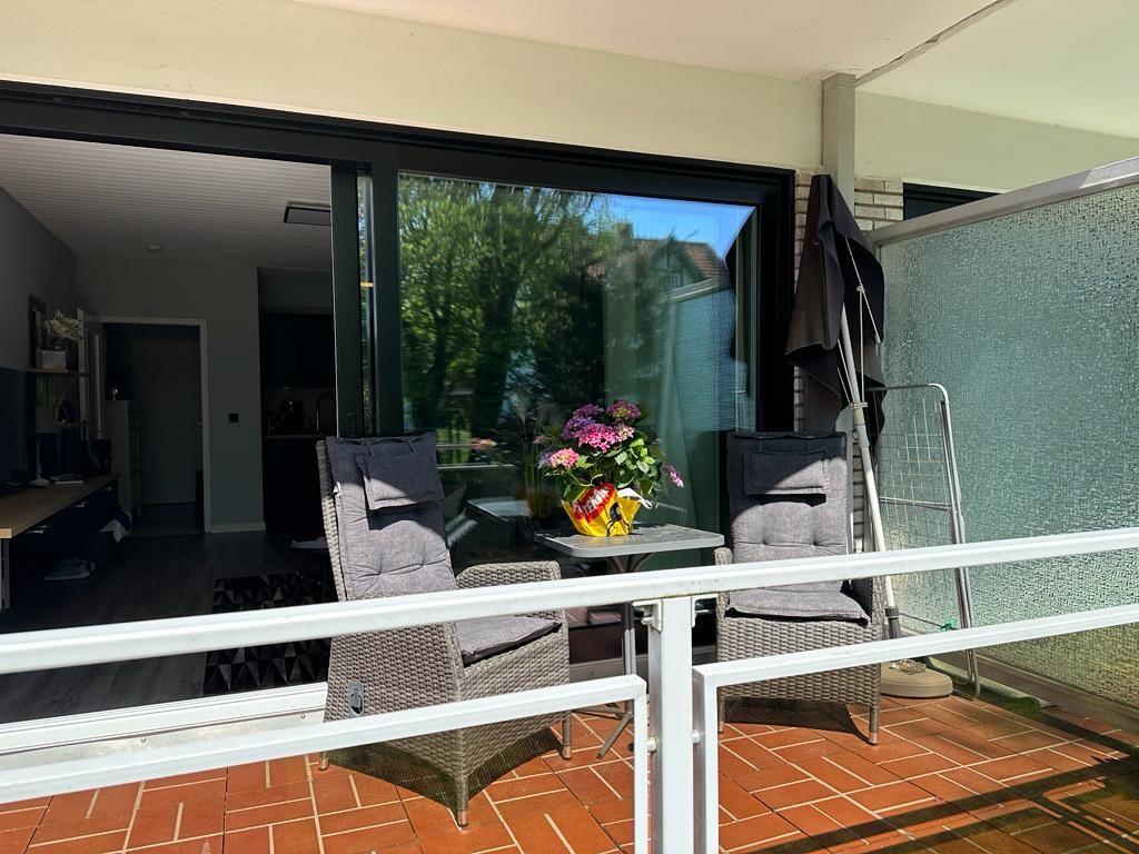 Terrace with two chairs and table, flowers and view into the house.