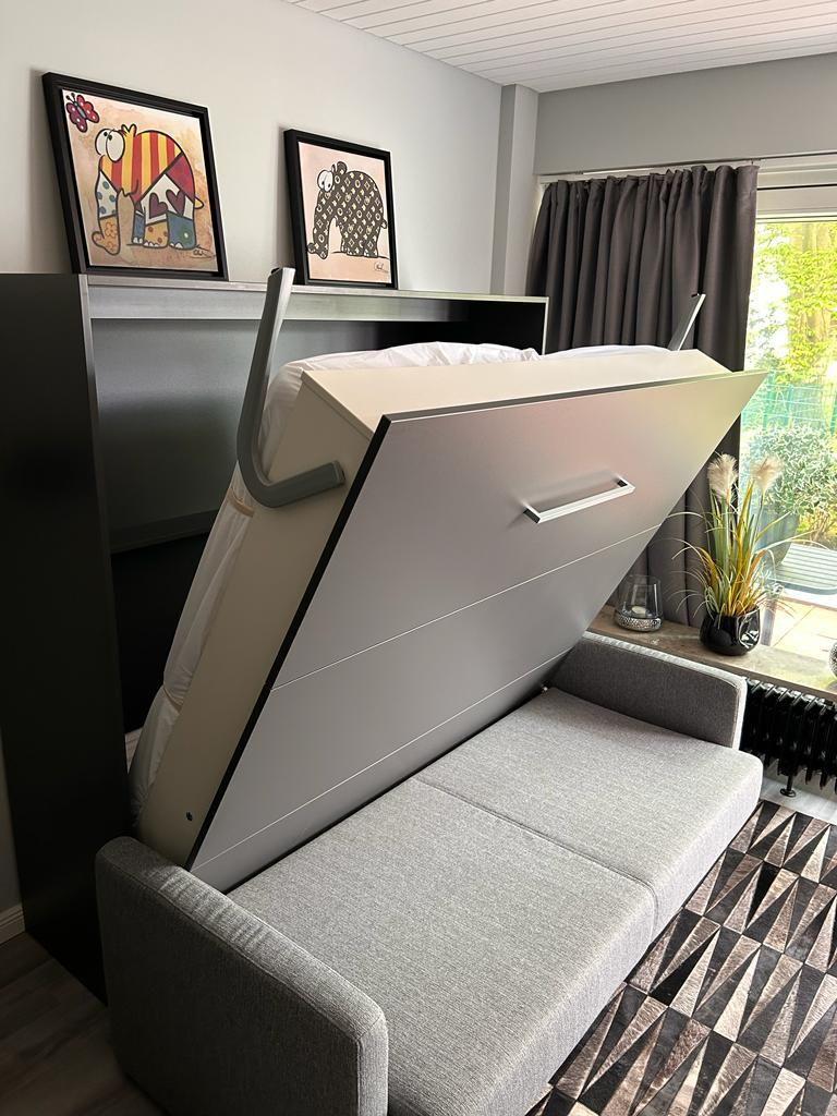 Sofa bed with storage, wall art, and window with curtains.