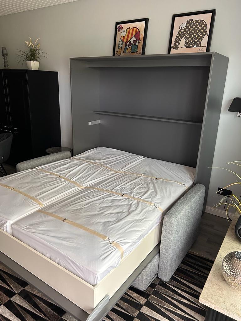 Bedroom with fold-down bed, wall shelf, and pictures on the wall.