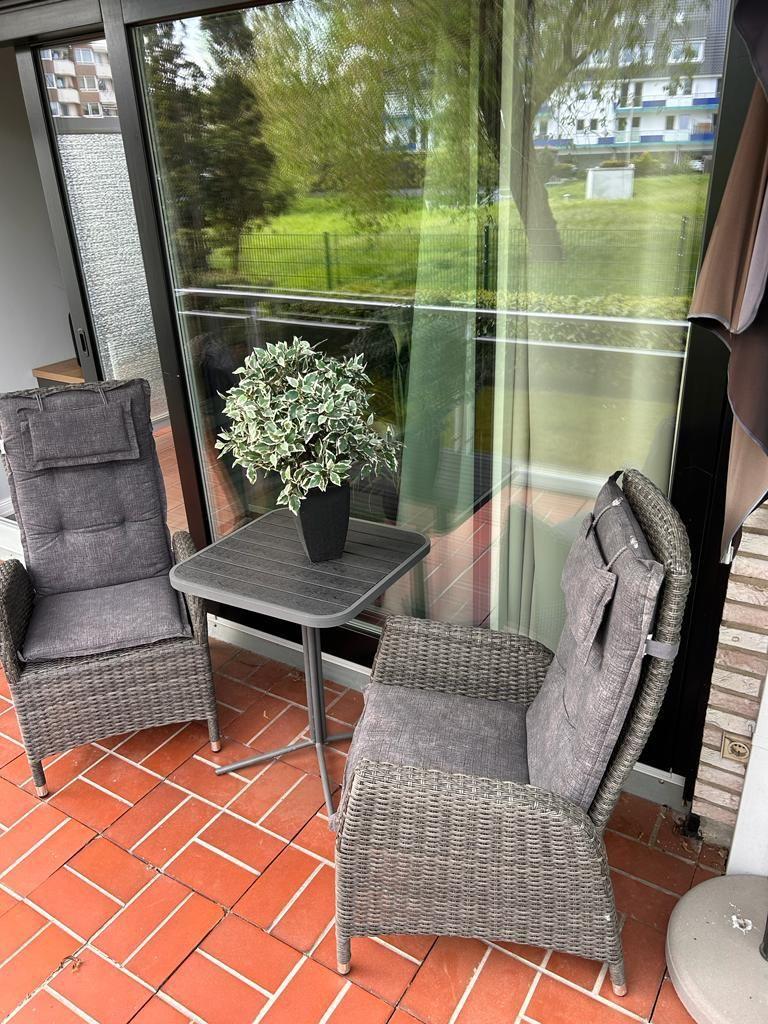 Terrace with two chairs, table, and plant. View of green area.