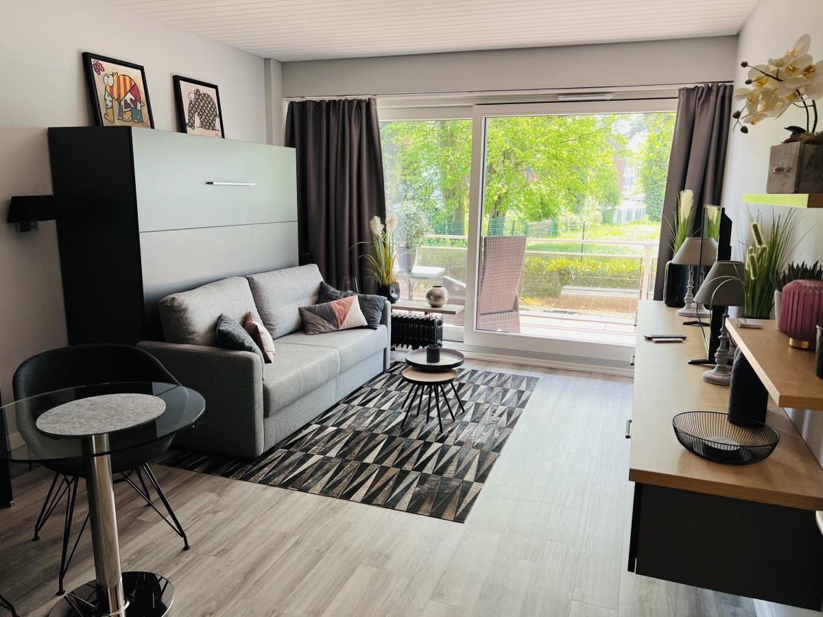 Living room with sofa, rug, and glass table. Access to terrace with garden view.