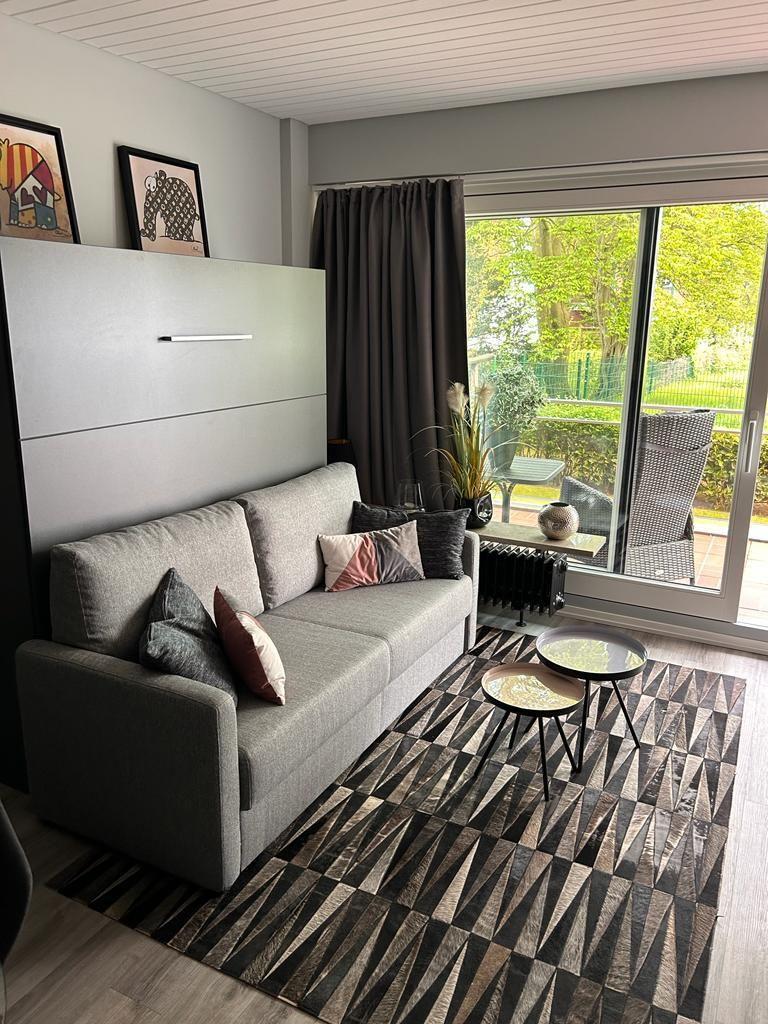 Living room with sofa, rug, and view of balcony