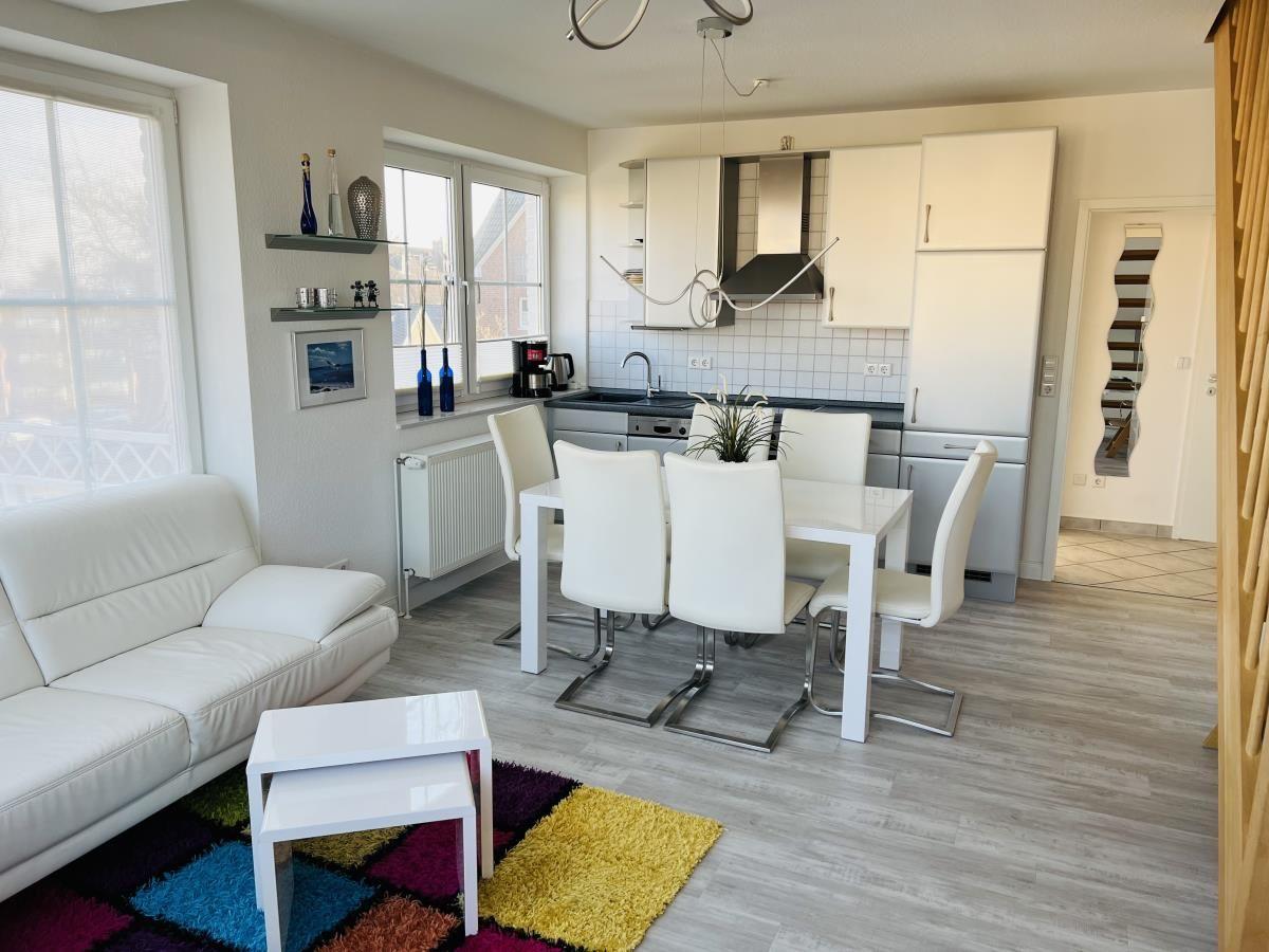 Wohn- und Essbereich mit weißem Sofa, Esstisch und Küchenzeile.
