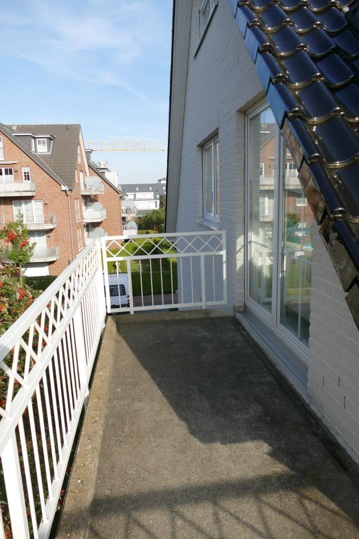 Terrasse mit weißer Brüstung und Sicht auf Wohngebiet.