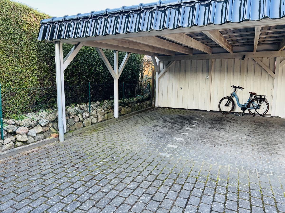 Carport mit blauem Dach und Fahrrad an der Wand.