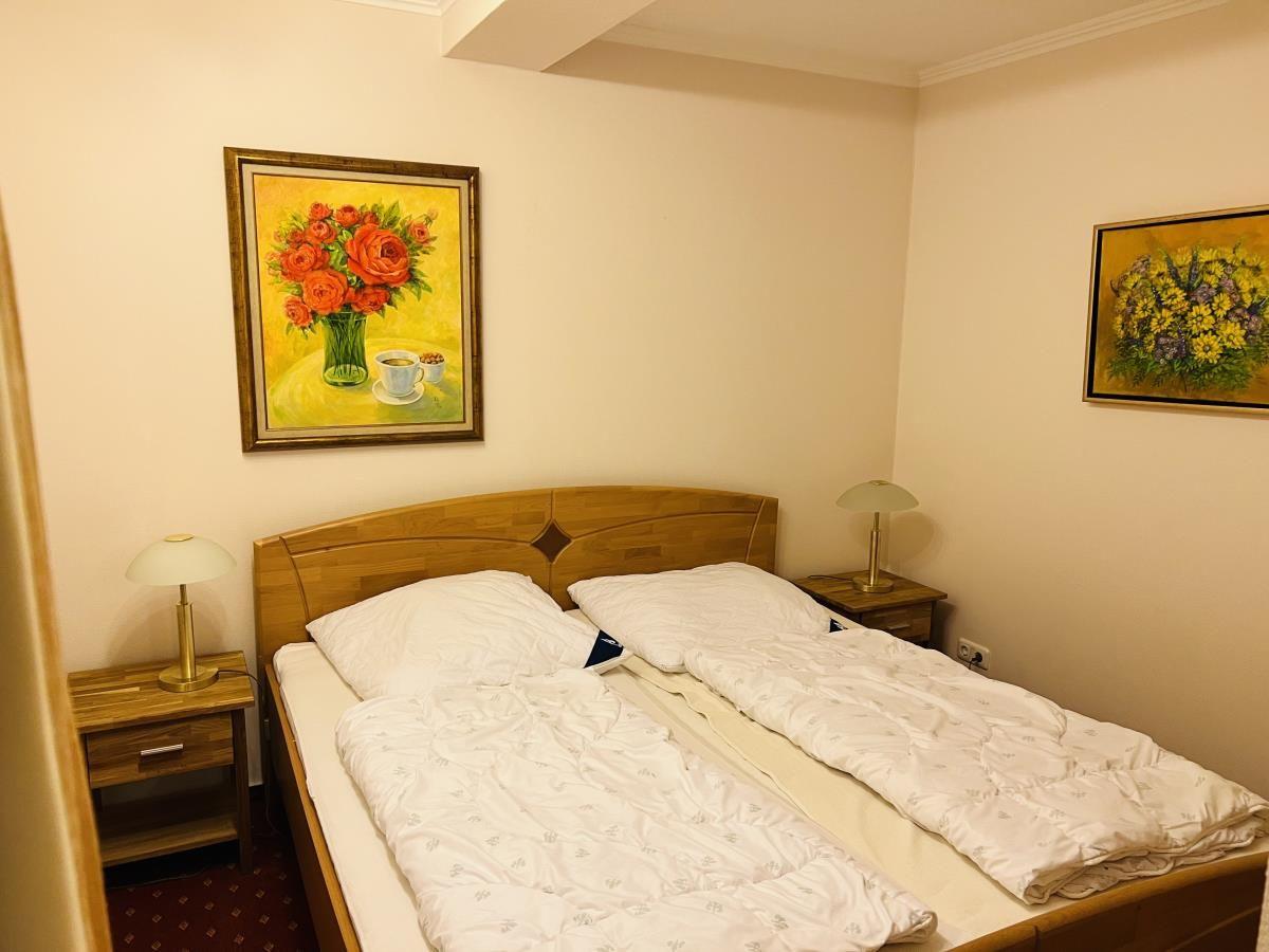 Schlafzimmer mit Doppelbett, zwei Nachttischen und Wandbildern.
