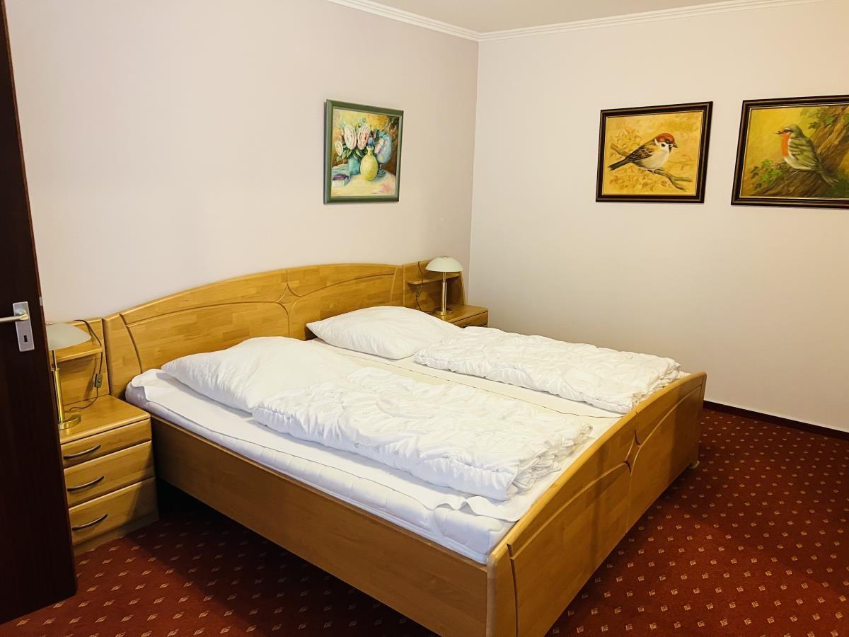 Ein Schlafzimmer mit Holzbett, zwei Nachttischen und Wandbildern.