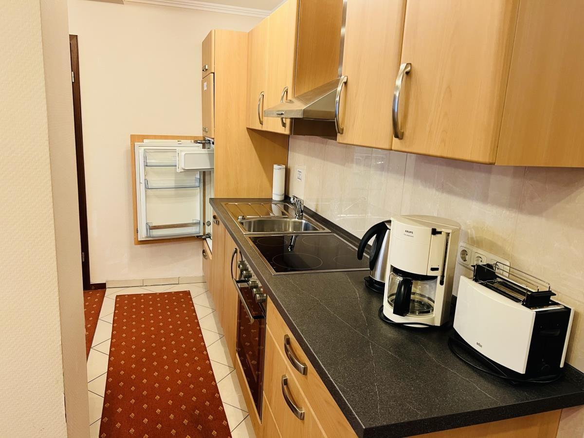 Küche mit Holzschränken, Kochfeld und Kühlschrank.