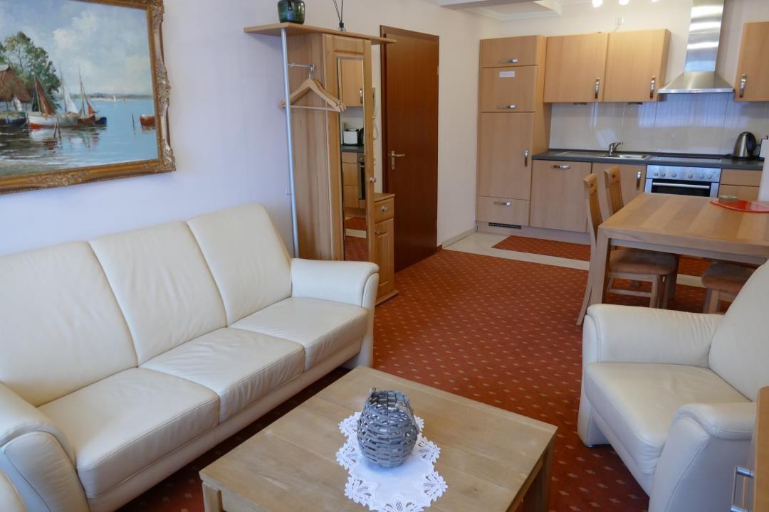Wohnzimmer mit Sofa, Sessel und Küchenbereich
