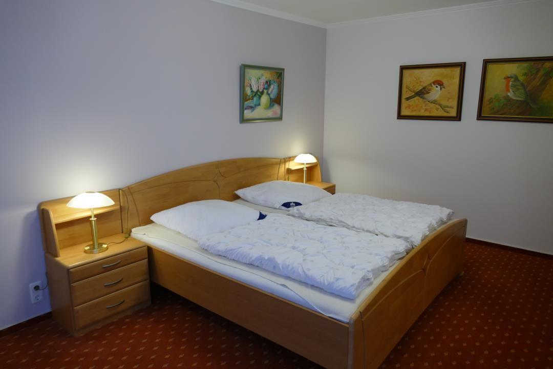 Ein Schlafzimmer mit Holzbett, Nachttischen und Wandbildern.