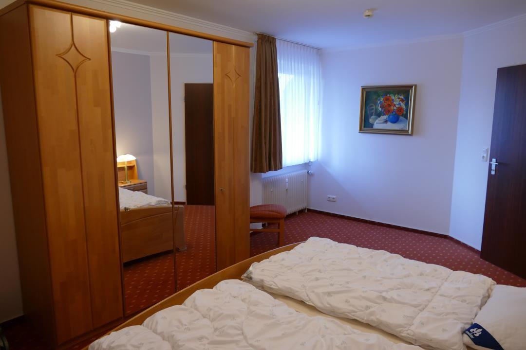 Schlafzimmer mit Doppelbett, Kleiderschrank und Fenster.