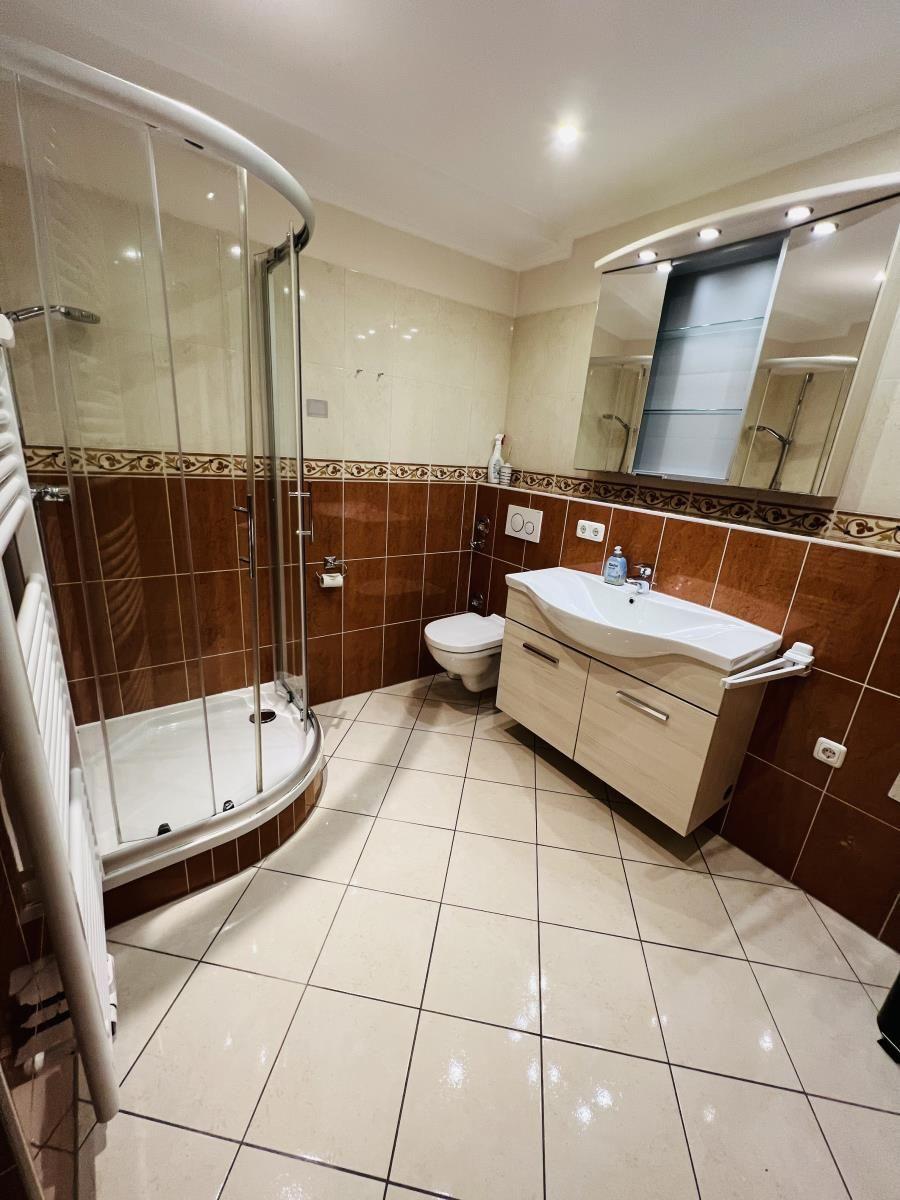 Badezimmer mit Dusche, Waschbecken und Toilette.