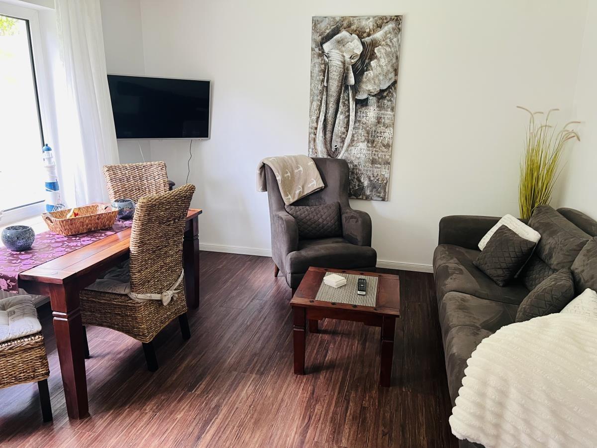 Wohnzimmer mit Sofa, Sessel, Esstisch und Wandbild