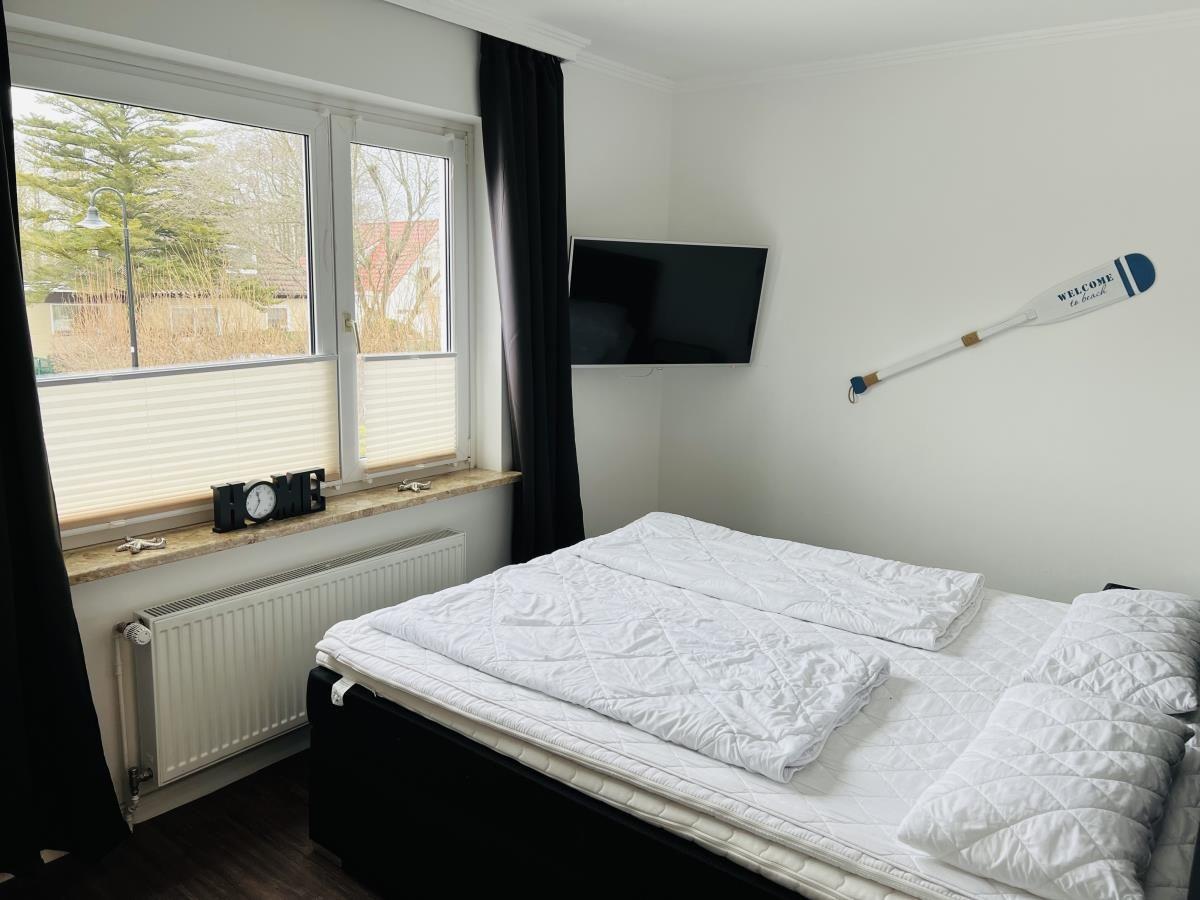 Schlafzimmer mit Bett, TV und Fenster mit Blick nach draußen.